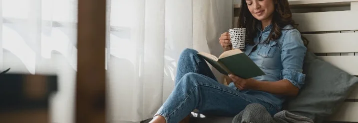 Person sitzt auf einem Sitzsack und liest ein Buch.